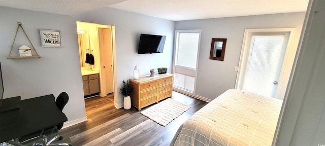 bedroom featuring dark wood-style floors, connected bathroom, and baseboards