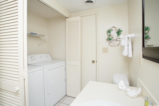 laundry area with light tile patterned floors and washing machine and clothes dryer