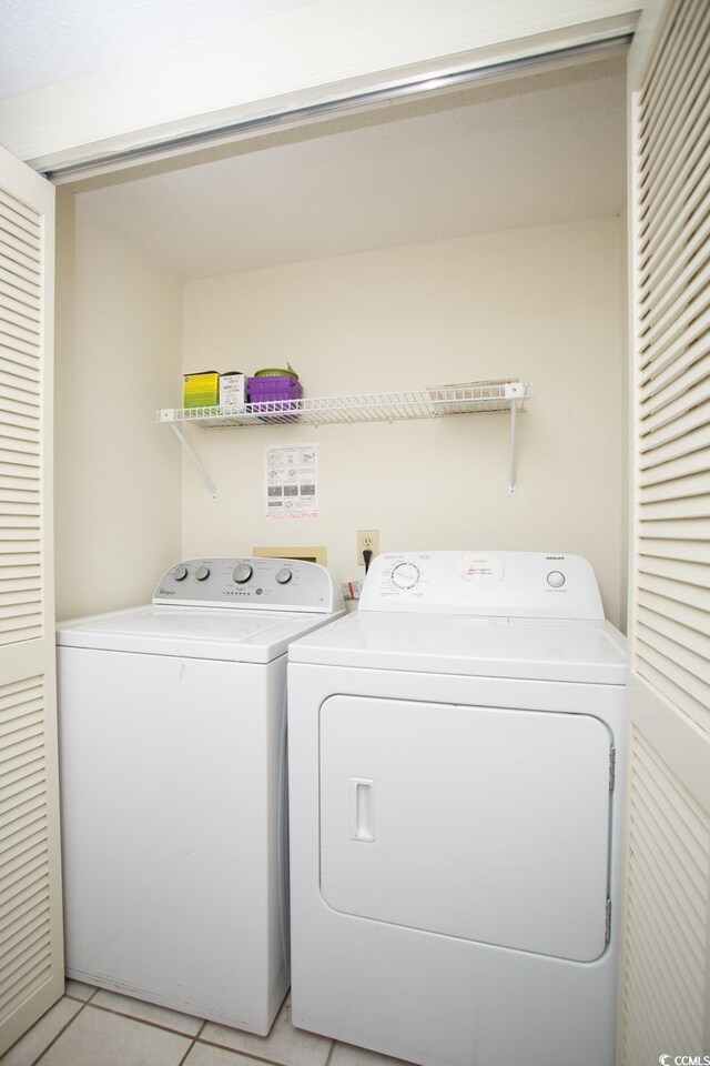 clothes washing area featuring light tile patterned flooring and washer and dryer