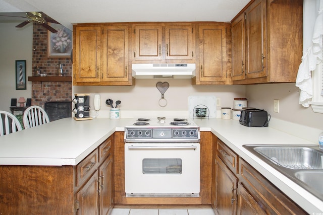 kitchen featuring white electric range oven, a breakfast bar, sink, kitchen peninsula, and ceiling fan