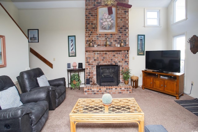 living room with a brick fireplace, light colored carpet, and ceiling fan