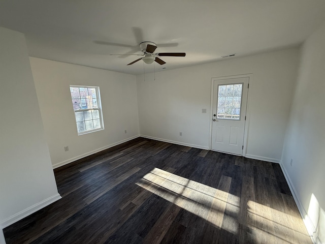 unfurnished room featuring ceiling fan, dark wood-style flooring, visible vents, and baseboards