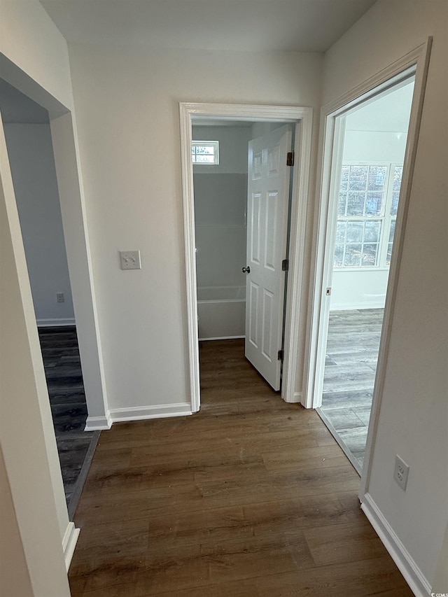 corridor with dark wood-style flooring and baseboards