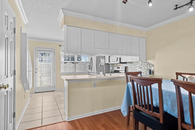 618 3rd Ave S Unit 4D, North Myrtle Beach, SC 29582 - kitchen with backsplash, white cabinetry, a peninsula, light countertops, and ornamental molding