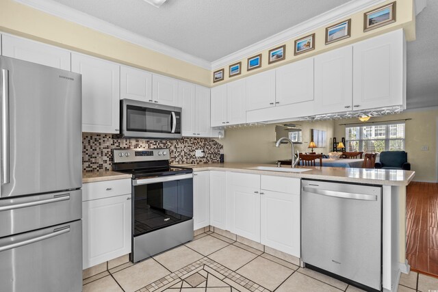 618 3rd Ave S Unit 4D, North Myrtle Beach, SC 29582 - kitchen with stainless steel appliances, a peninsula, light countertops, crown molding, and white cabinets