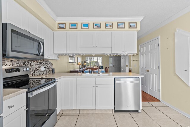 618 3rd Ave S Unit 4D, North Myrtle Beach, SC 29582 - kitchen featuring appliances with stainless steel finishes, a sink, ornamental molding, a peninsula, and light countertops