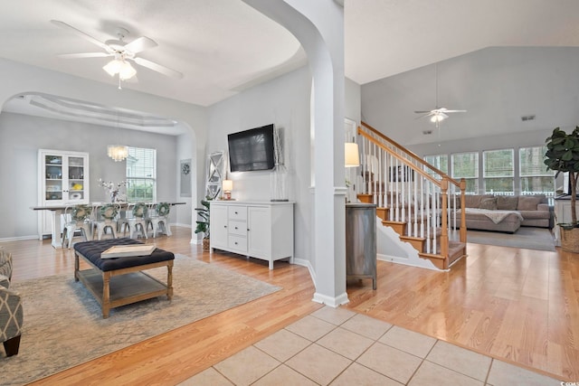 living room with light wood-type flooring, a healthy amount of sunlight, and ceiling fan with notable chandelier