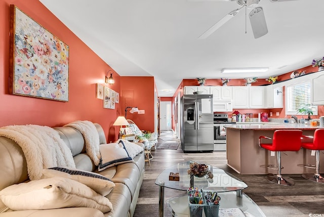 living room featuring ceiling fan, sink, and dark hardwood / wood-style floors