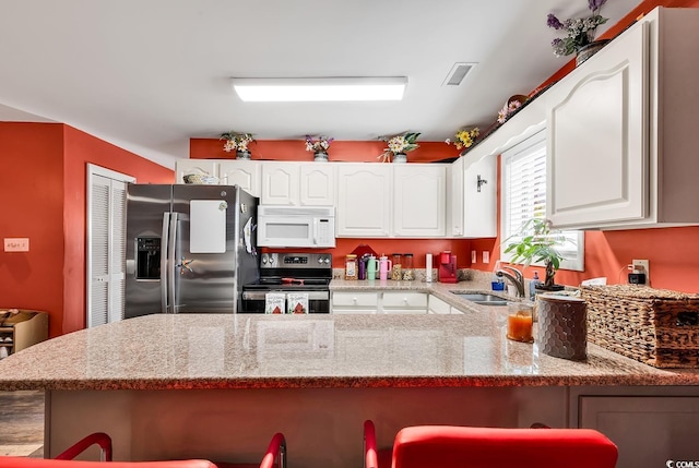 kitchen with white cabinets, appliances with stainless steel finishes, sink, and a breakfast bar area