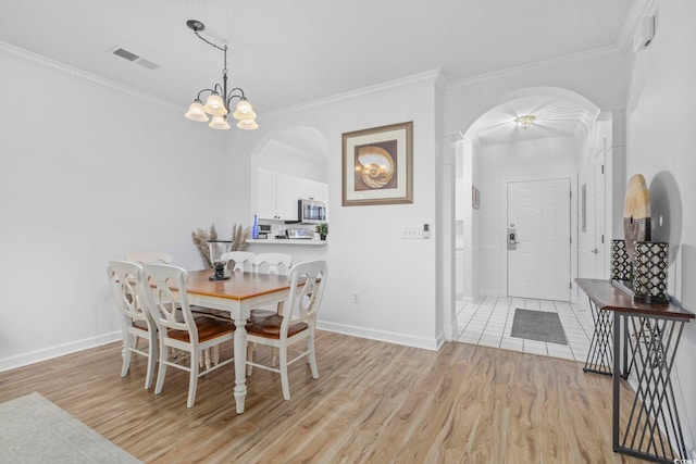 dining space featuring light hardwood / wood-style flooring, crown molding, and a notable chandelier