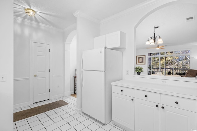 kitchen featuring a textured ceiling, white cabinets, white refrigerator, light tile patterned flooring, and crown molding