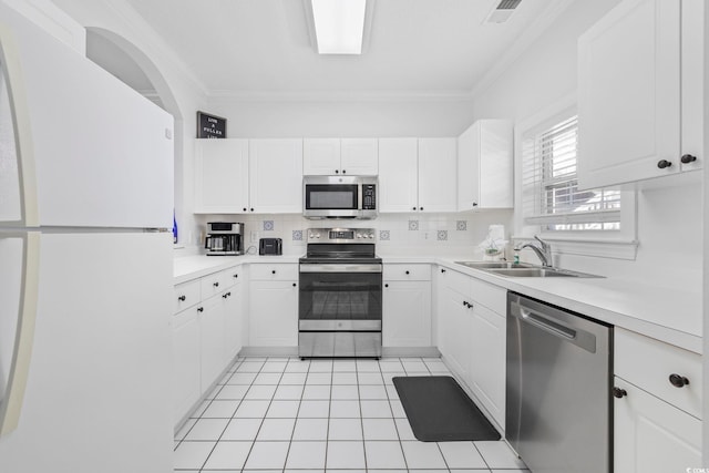 kitchen featuring appliances with stainless steel finishes, ornamental molding, white cabinets, and sink