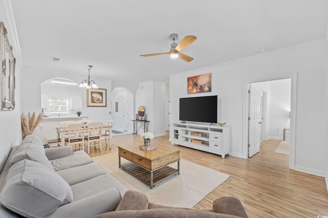 living room featuring light wood-type flooring, crown molding, and ceiling fan with notable chandelier