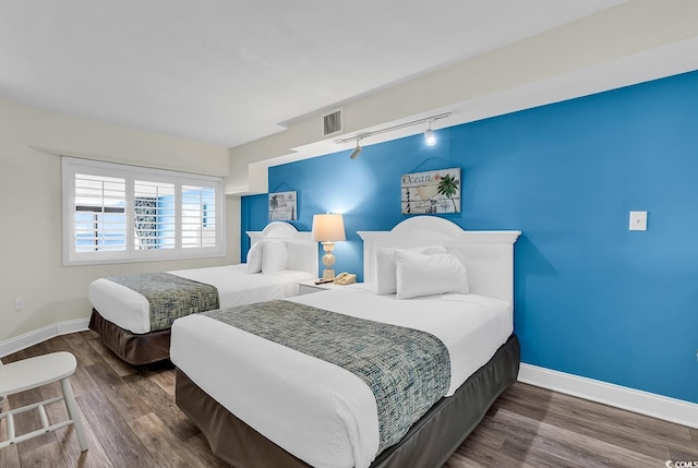 bedroom featuring dark hardwood / wood-style floors and track lighting