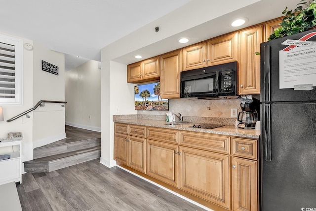 kitchen featuring tasteful backsplash, black appliances, sink, light wood-type flooring, and light stone counters