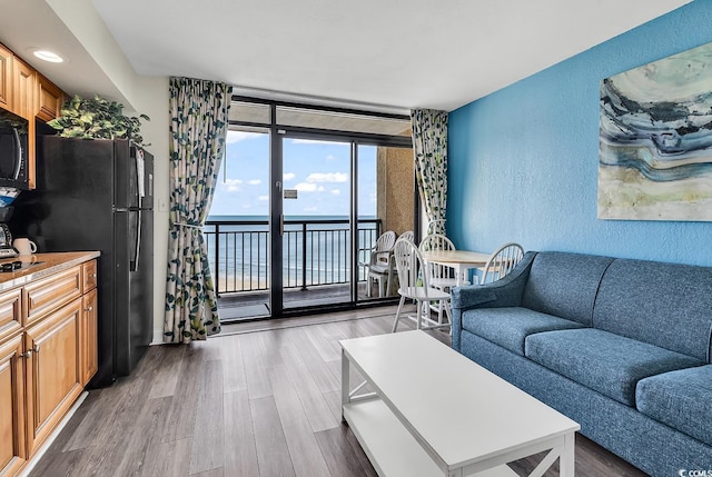 living room featuring a water view, expansive windows, and wood-type flooring