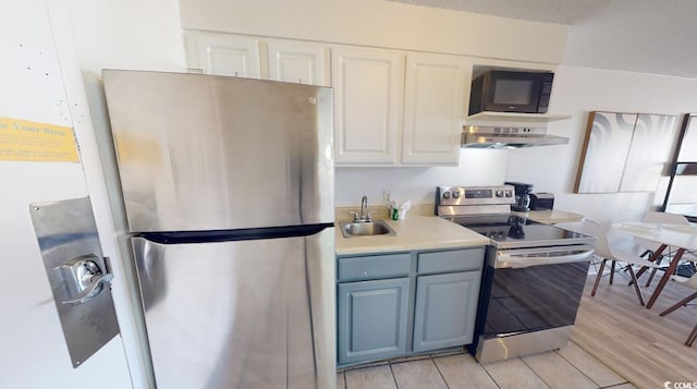 kitchen with exhaust hood, light hardwood / wood-style floors, sink, appliances with stainless steel finishes, and white cabinets