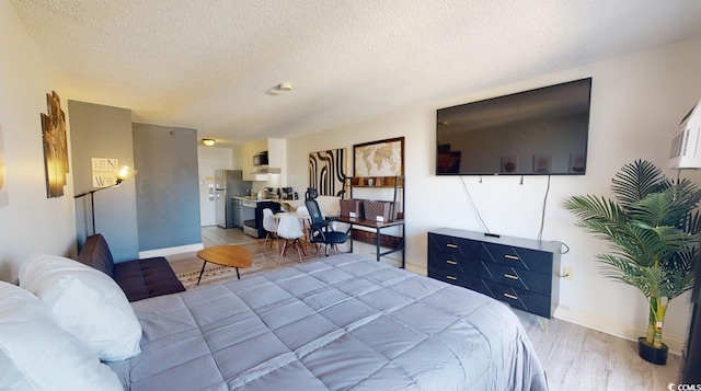 bedroom with wood-type flooring, stainless steel fridge, and a textured ceiling