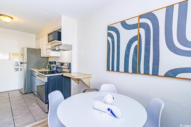 kitchen with sink, blue cabinetry, a textured ceiling, stainless steel range with electric stovetop, and white cabinets