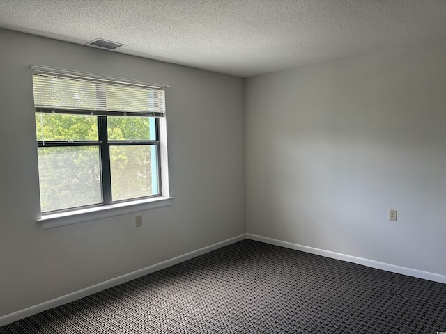 carpeted empty room featuring visible vents, a textured ceiling, and baseboards