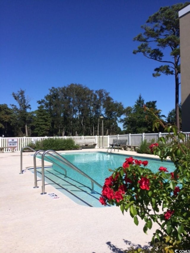 community pool with a patio area and fence