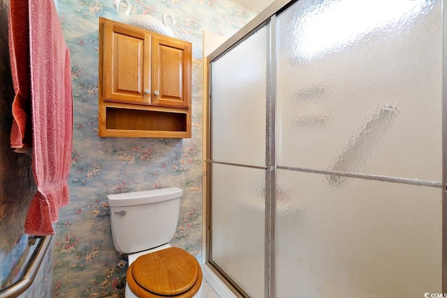 full bathroom featuring toilet, wallpapered walls, and a stall shower