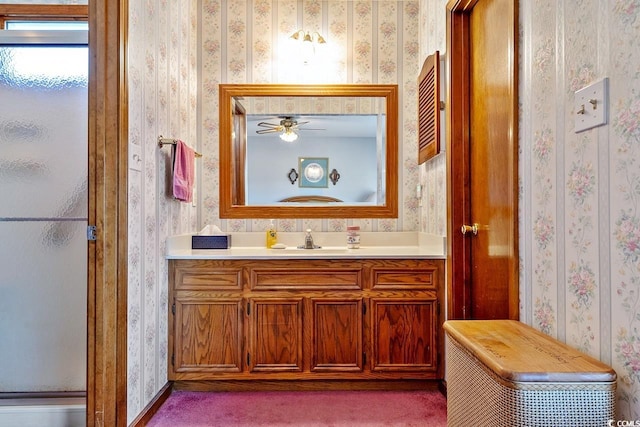 bathroom with a shower with shower door, vanity, and wallpapered walls