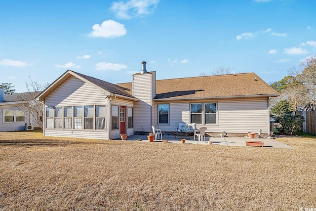 back of house featuring a patio area, a chimney, a sunroom, and a lawn