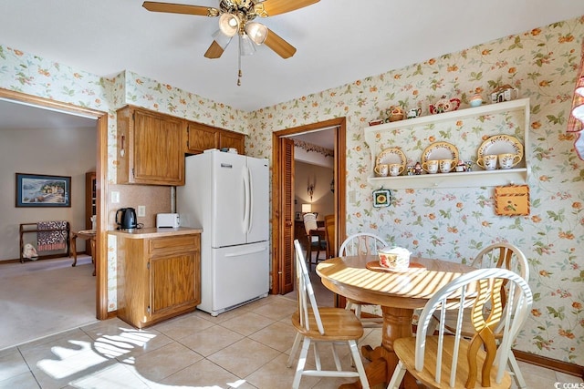 kitchen featuring wallpapered walls, light tile patterned floors, a ceiling fan, freestanding refrigerator, and light countertops