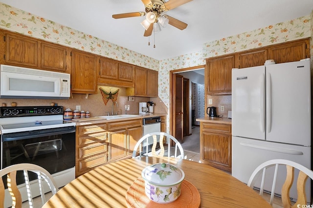 kitchen with white appliances, light countertops, a sink, and wallpapered walls