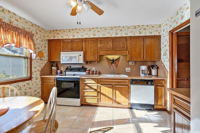 kitchen featuring a sink, white appliances, light countertops, and wallpapered walls