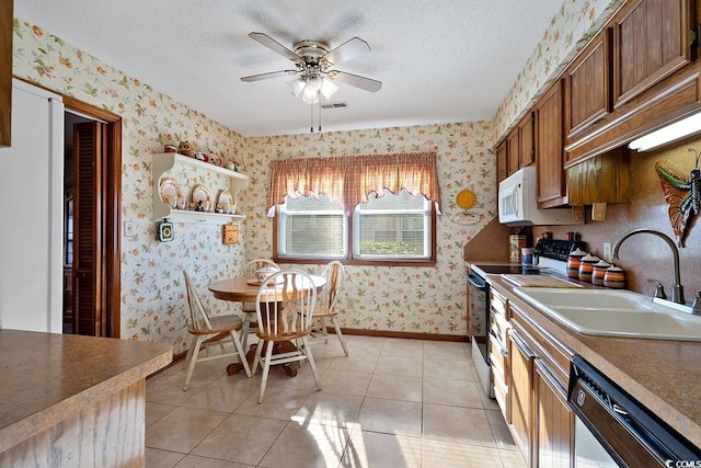 kitchen featuring wallpapered walls, light tile patterned floors, white appliances, a textured ceiling, and a sink