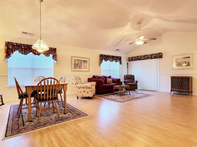 dining room with ceiling fan with notable chandelier, hardwood / wood-style floors, and lofted ceiling