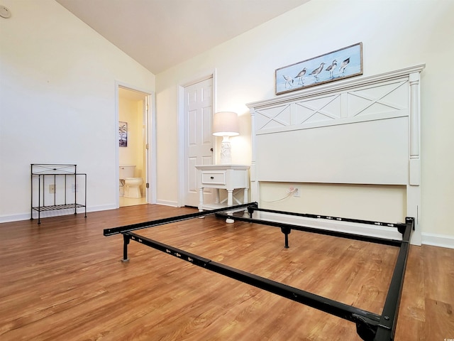 interior space featuring hardwood / wood-style flooring, connected bathroom, and lofted ceiling