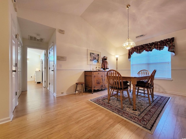 dining space featuring light wood-type flooring, lofted ceiling, and a notable chandelier