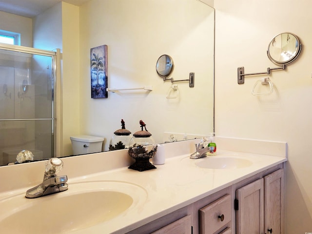 bathroom featuring toilet, vanity, and a shower with door