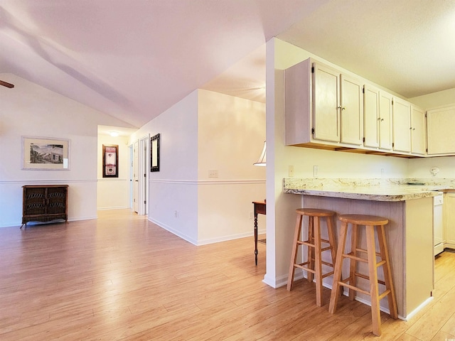 kitchen with lofted ceiling, dishwasher, kitchen peninsula, light wood-type flooring, and a breakfast bar area