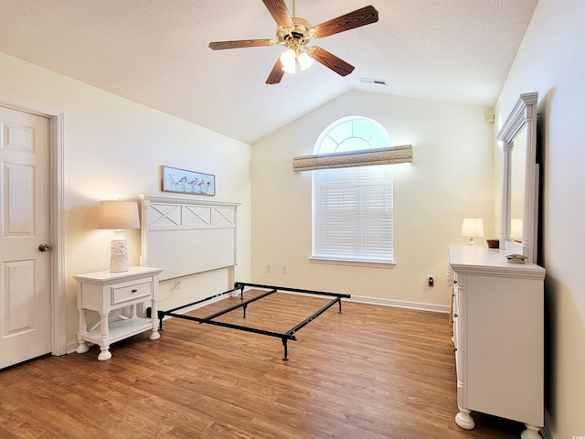 bedroom featuring a textured ceiling, light hardwood / wood-style flooring, and vaulted ceiling