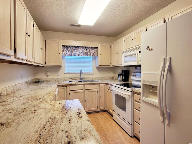 kitchen with sink, white appliances, light hardwood / wood-style flooring, and a textured ceiling