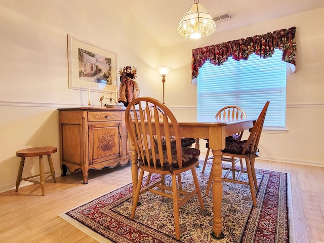 dining area with light wood-type flooring, lofted ceiling, and a notable chandelier