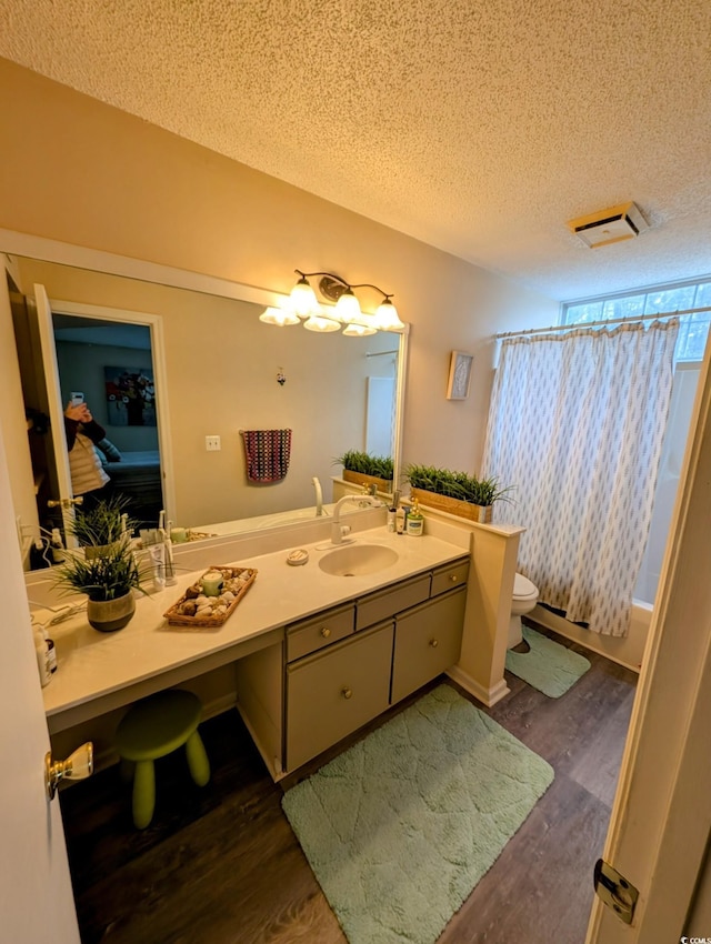 full bathroom featuring toilet, vanity, hardwood / wood-style floors, a textured ceiling, and shower / bath combo with shower curtain