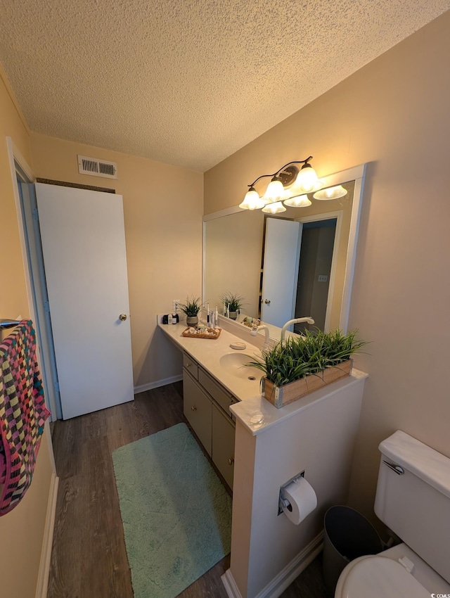 bathroom with a textured ceiling, toilet, hardwood / wood-style flooring, and vanity