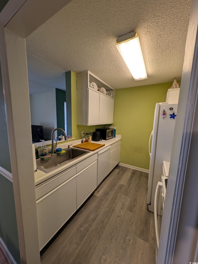 kitchen featuring stove, dark hardwood / wood-style flooring, a textured ceiling, white cabinets, and sink