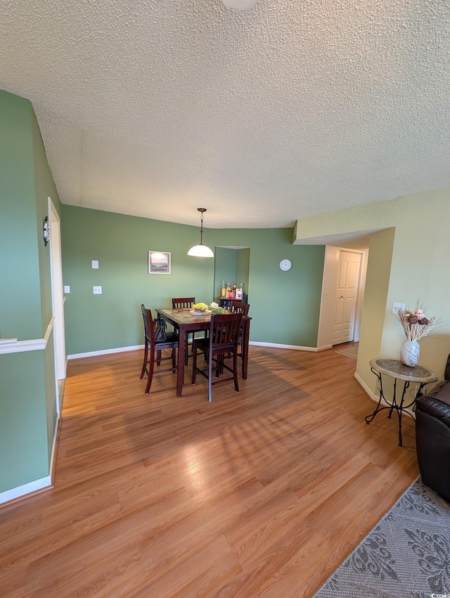 dining area with a textured ceiling and light hardwood / wood-style flooring