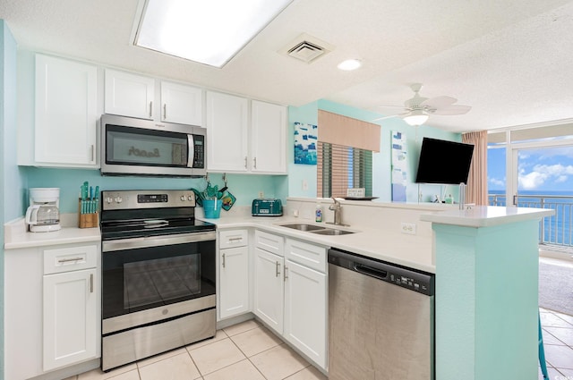 kitchen with visible vents, white cabinets, appliances with stainless steel finishes, a peninsula, and a sink