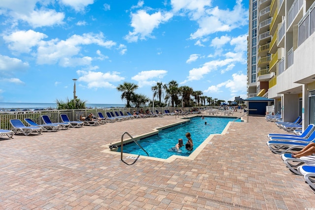 community pool with a patio area and fence