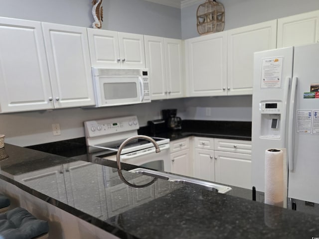 kitchen with white appliances, white cabinets, dark stone counters, ornamental molding, and kitchen peninsula