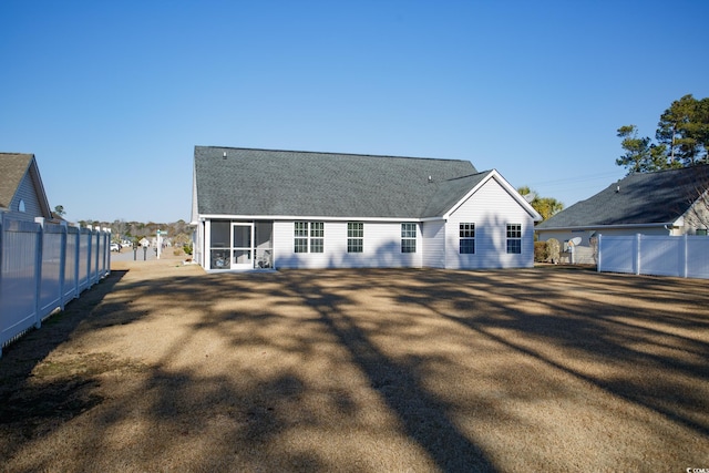 rear view of property featuring fence, roof with shingles, and a sunroom