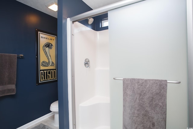 full bathroom featuring tile patterned flooring, a shower stall, toilet, and baseboards