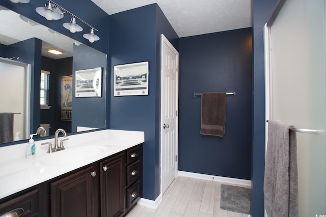 bathroom featuring vanity, wood finished floors, baseboards, and a textured ceiling